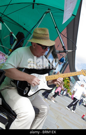 Un samedi dans le centre-ville de Manchester de la chaleur du soleil fait ressortir l'un des nombreux musiciens de rue. Banque D'Images