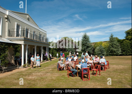 Groupe de personnes prendre des rafraîchissements lors d'une garden party dans le parc d'une grande maison en Angleterre. Banque D'Images