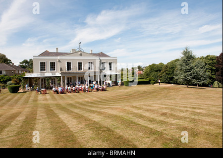 Groupe de personnes bénéficiant d'une garden party dans le parc d'une grande maison en Angleterre. Banque D'Images