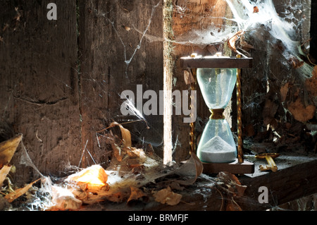 Temps passé - sandclock concept et une clé oubliée dans un coin sale avec des feuilles et d'araignées. Banque D'Images