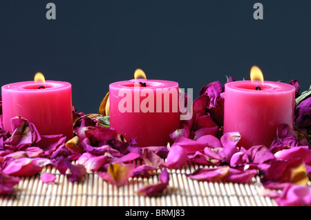 Bougies allumées près de pétales de rose Banque D'Images