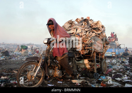 Un travailleur est le transport d'ordures sacs vides retour à Stung Meanchey recycleurs à la décharge de Phnom Penh, Cambodge. Banque D'Images