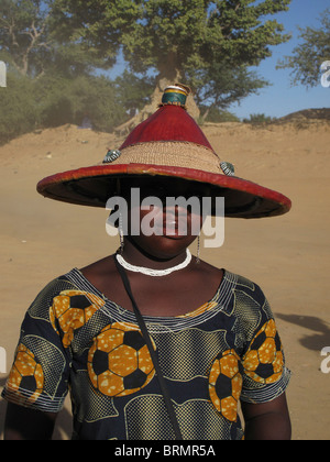 Une femme africaine portant un chapeau traditionnel qui est l'ombre ses yeux et un chemisier qui a un modèle de football sur elle Banque D'Images