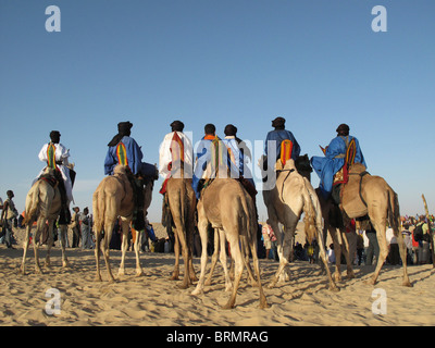 Les hommes touareg sur des chameaux vêtus de robes traditionnelles en arrivant à la fête annuelle dans le désert Banque D'Images