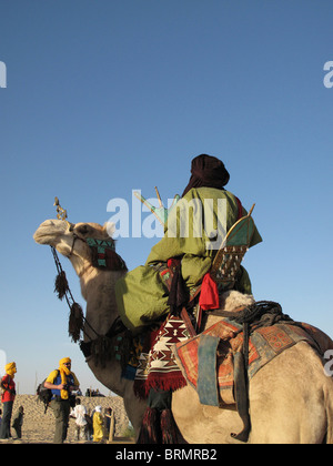 L'homme sur un chameau touareg vêtus de robes traditionnelles en regardant un spectacle au festival annuel dans le désert Banque D'Images