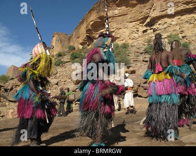 Les danseurs Dogon portant des masques et de longues jupes de paille colorée effectuant une danse de cérémonie Banque D'Images