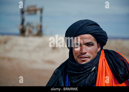 Portrait d'un homme berbère debout devant un vieux puits en un lieu de repos. Banque D'Images