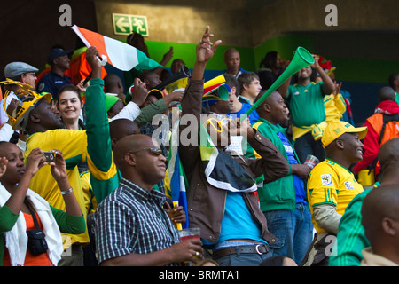 Les partisans de soccer en agitant et en soufflant les vuvuzelas pour célébrer un but marqué par la Cote d'Ivoire à l'durant la Coupe du Monde 2010 Banque D'Images