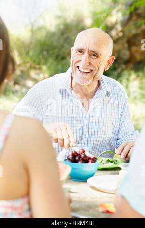 Smiling older man at picnic table Banque D'Images