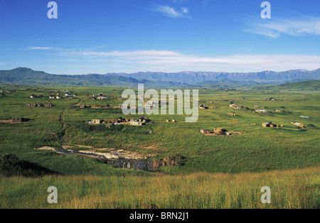 Injasuti Kwazulu Natal montrant les terres rurales avec des huttes zoulou et le Drakensberg escarpement dans l'arrière-plan Banque D'Images