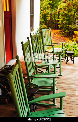 Chaises à bascule vert sur porche de ferme rurale blanche Banque D'Images