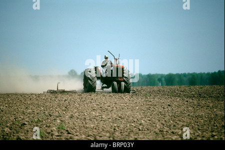 Printemps - Agriculteur sur de vieux tracteur rouge (herses casse vers le haut) pour préparer le sol à la plantation en terre riche de rivière Missouri Banque D'Images