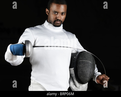 Portrait d'un tireur portant une flexion uniforme d'escrime l'épée dans ses mains. Isolé sur fond noir Banque D'Images