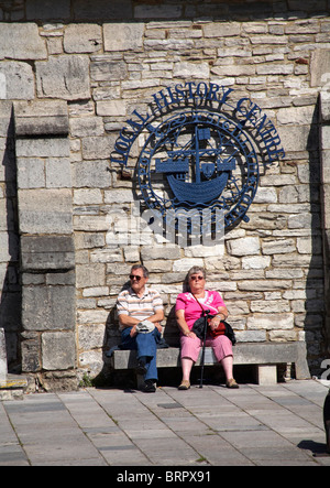 Couple assis sur un banc à l'extérieur de l'histoire locale dans le centre de Poole Banque D'Images