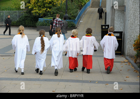 Six choristes, toi garçons et trois filles dans leurs robes en marche une ligne vers un métro à Wolverhampton Banque D'Images