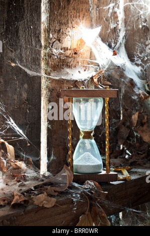 Temps passé - sandclock concept et une clé oubliée dans un coin sale avec des feuilles et d'araignées. Banque D'Images