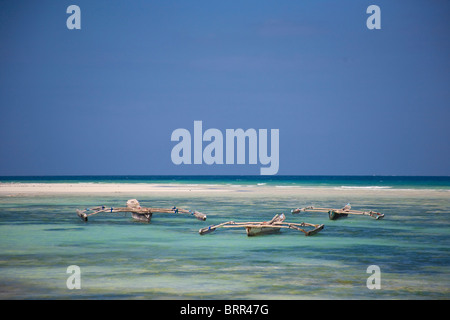 Scène de plage avec la pêche aux tangons bateaux amarrés dans les eaux peu profondes au large de l'île de Mnemba Banque D'Images