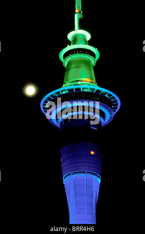 La Sky tower à Auckland tower éclairés en bleu et vert de nuit vue contre la pleine lune Banque D'Images