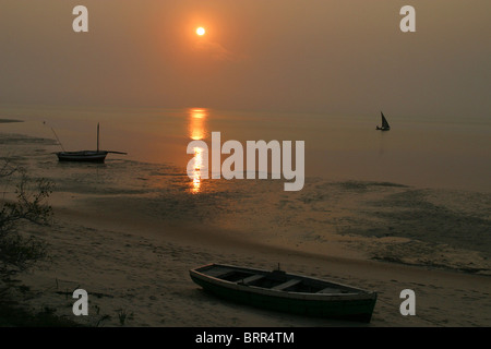 Les pêcheurs sur un dhow au coucher du soleil, d'autres bateaux de pêche sur le sable Banque D'Images