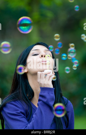 Belle jeune femme faisant des bulles dans le vert Banque D'Images