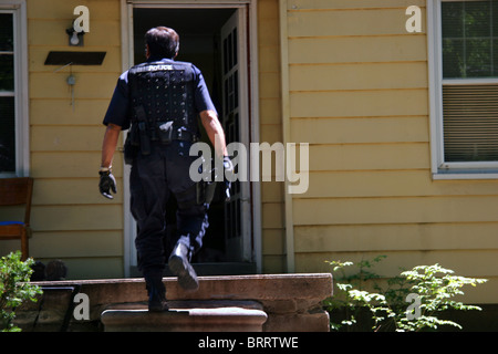 Agent de la police de Detroit une maison appraoches unité stupéfiants lors d'un raid avec un médicament appelé gun. Banque D'Images