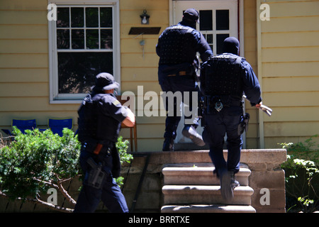 Agent de la police de Detroit unité stupéfiants courir vers une maison au cours d'un raid de la drogue. Banque D'Images