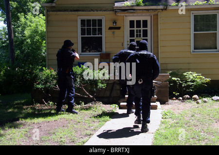 Agent de la police de Detroit les stupéfiants approche de l'unité d'une maison au cours d'un raid de la drogue. Banque D'Images
