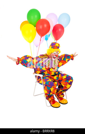 Funny clown volant par l'air dans sa chaise avec des ballons d'hélium attachés. Isolé sur blanc. Banque D'Images