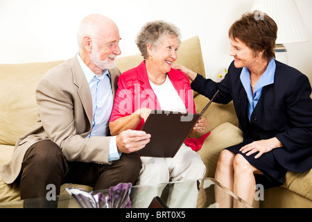 Senior couple écoute une vendeuse ou conseiller financier dans leur maison. Banque D'Images