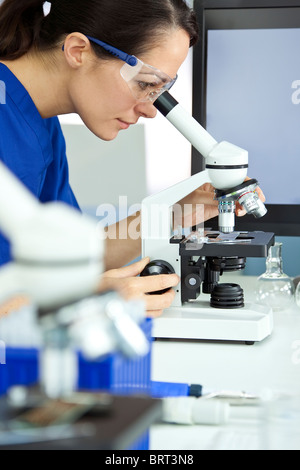 Une belle femme chercheur médical ou scientifique, à l'aide de son microscope dans un laboratoire. Banque D'Images