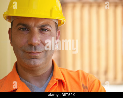 Portrait of mid adult worker standing près de conteneurs de fret et à la recherche à l'appareil photo. Vue avant, de forme horizontale, copy space Banque D'Images