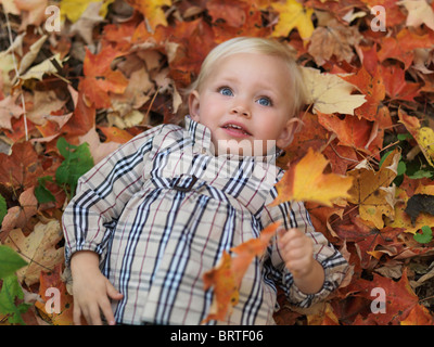 Deux ans, fille, et couché sur des feuilles à l'automne nature Banque D'Images