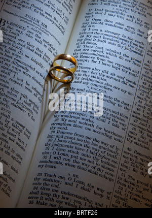 Anneaux de mariage d'or de la création d'une forme de coeur ombre sur une Bible Banque D'Images