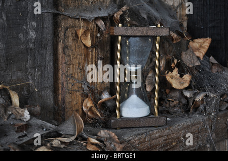 Temps passé - sandclock concept et une clé oubliée dans un coin sale avec des feuilles et d'araignées. Banque D'Images