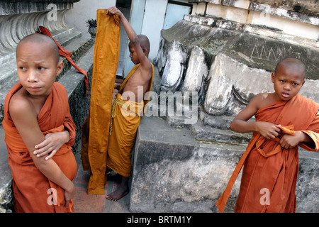 Les jeunes moines bouddhistes khmers sont mise sur leurs robes orange avant une cérémonie dans un temple de Phnom Penh, au Cambodge.. Banque D'Images