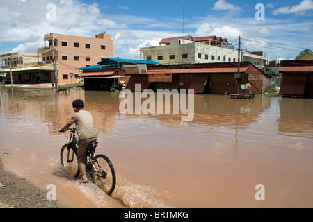 Un garçon sur un vélo par le biais de l'eau boueuse après la crue historique de 2009 à Siem Reap, Cambodge. Banque D'Images