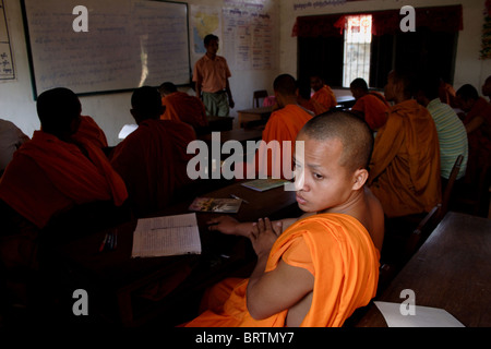 Un moine bouddhiste est à la recherche d'une fenêtre de classe à classe école secondaire à Wat Bangkok Temple de Kampong Cham, au Cambodge. Banque D'Images