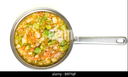 Bouillon de légumes rustiques et le jambon dans une casserole en acier inoxydable isolé sur blanc. Banque D'Images