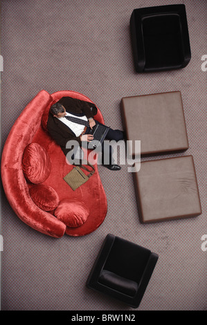 Man in suit tapant sur son ordinateur portable sur un canapé rouge Vue de dessus Banque D'Images