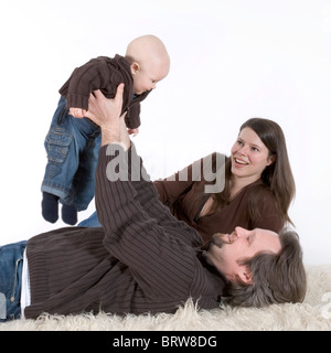 La famille, père, mère et bébé sur un tapis flokati Banque D'Images