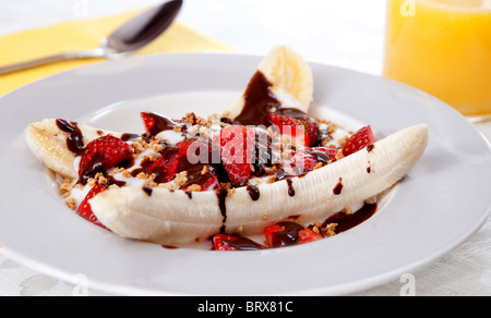 Une assiette santé de banana split avec du yogourt faible en gras, les fraises et sucre ajouté Banque D'Images