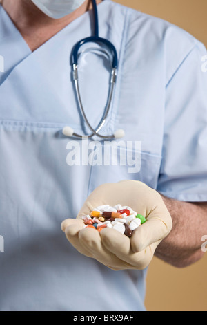Médecin tenant un grand nombre de comprimés dans sa main Banque D'Images