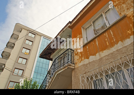 Un vieux négligé deux étages immeuble d'un nouveau appartement moderne bâtiment derrière elle. Banque D'Images