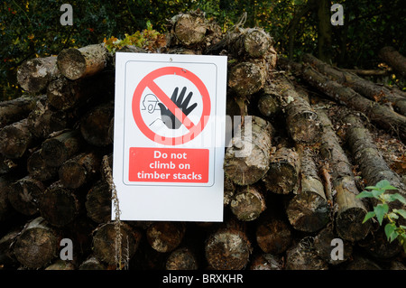 Avis d'avertissement informant les gens de ne pas monter sur la pile de bois dans un environnement boisé Banque D'Images