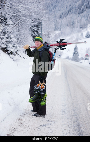 St Anton am Arlberg, Tyrol, Autriche. La réalisation de bottes de ski skieur avec les skis sur l'épaule couverte de neige sur la route alpine en hiver Banque D'Images