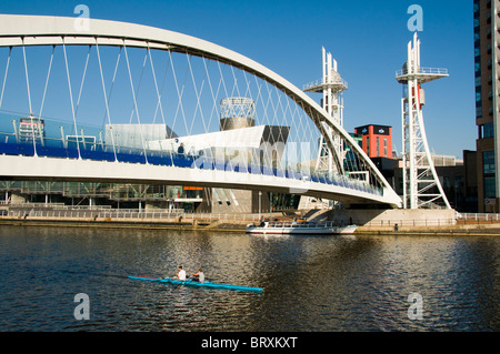 Sculling (aviron) sur le Manchester Ship Canal, sous la passerelle du millénaire (Lowry), Salford Quays, Manchester, UK Banque D'Images