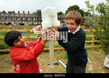 Les enfants de créer des modèles à partir de déchets d'emballage lors d'une visite à l'attribution de locaux, Bradford, West Yorkshire Banque D'Images