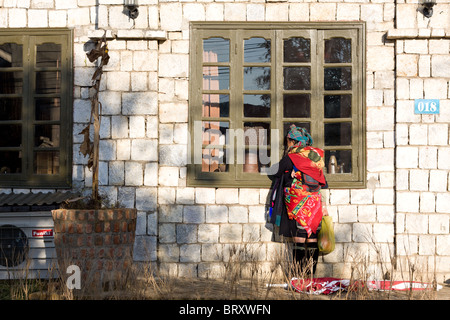 Une femme Hmong noir avec son bébé dans la fenêtre d'un restaurant par les pairs dans l'espoir de trouver un touriste pour essayer de vendre ses marchandises à Banque D'Images