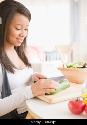 Smiling mixed race woman cutting vegetables Banque D'Images