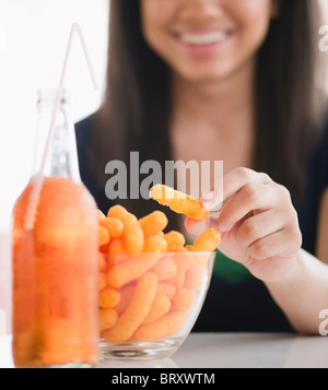 Close up of mixed race woman eating cheese puffs Banque D'Images